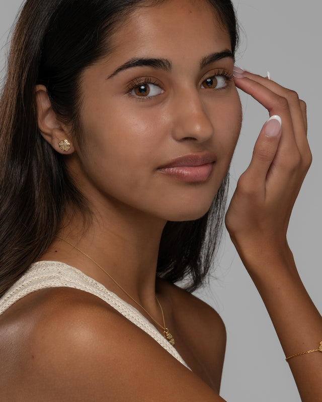 Cara clover set worn with a cream knit top, showing the pendant and matching studs