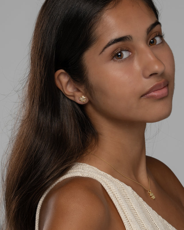 Model wearing the Cara clover necklace and stud earrings in gold