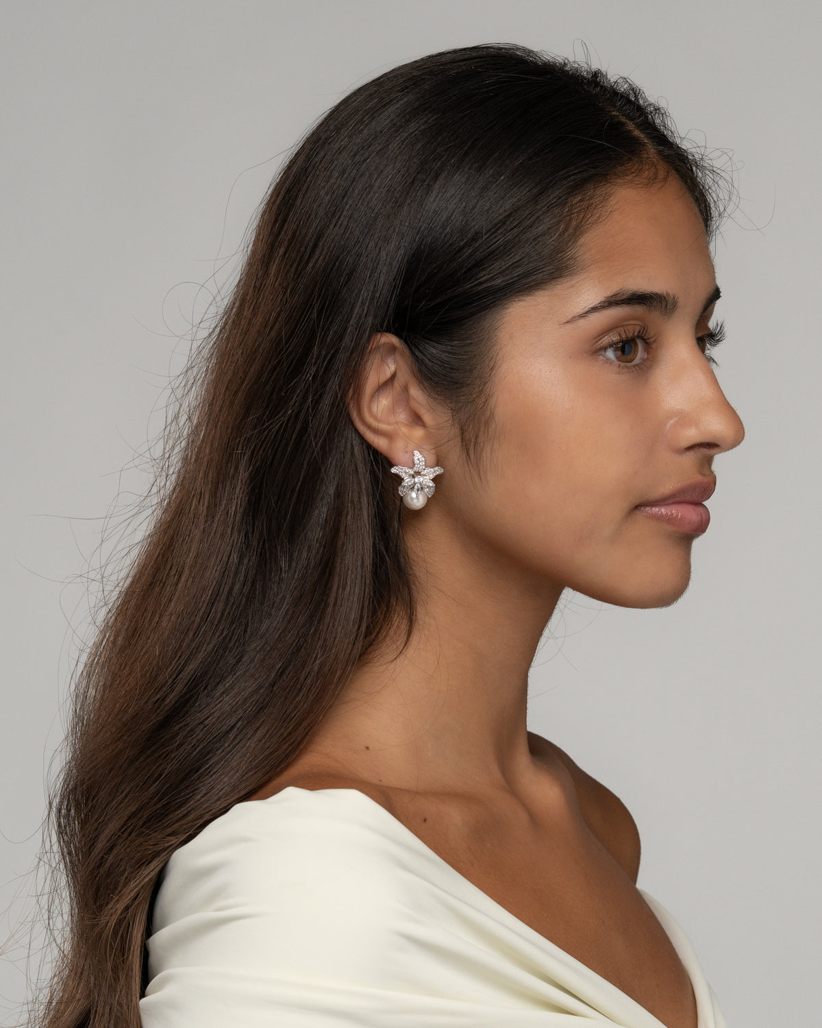 Side view of the Cattleya pearl earrings on the ear, showing the pearl beneath the petals