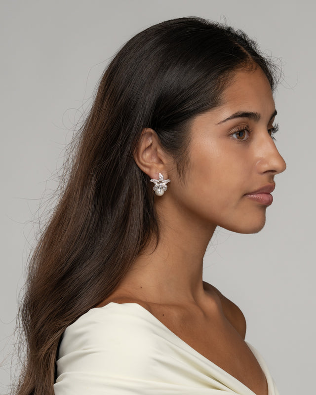 Side view of the Cattleya pearl earrings on the ear, showing the pearl beneath the petals
