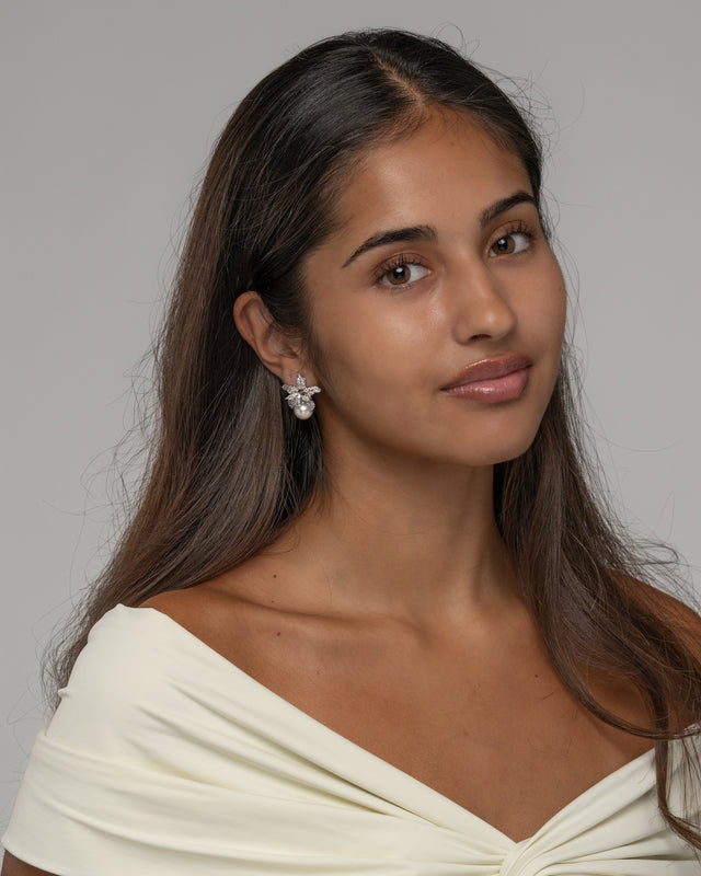 Model wearing the Cattleya pearl flower earrings with an off shoulder ivory dress