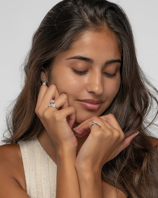 Chloe pearl drop earrings styled with silver rings, hands framing the face
