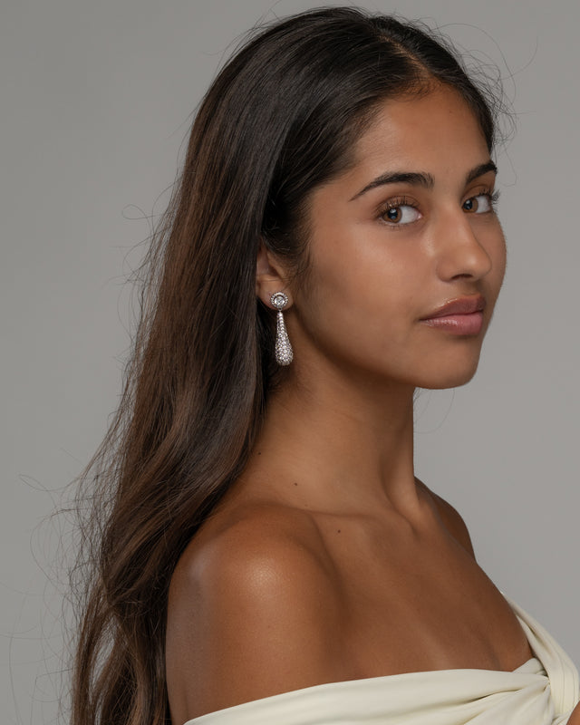 Side view of the Diorra drop earrings on the ear with an off shoulder ivory top