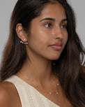 Model wearing the Jia star earrings in gold with a cream knit top