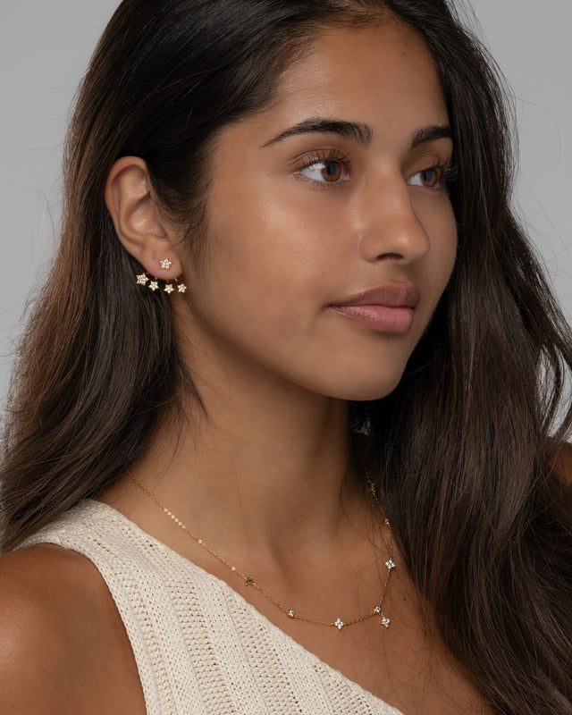 Model wearing the Jia star earrings in gold with a cream knit top