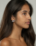 Side view of the Nia claw earrings on the ear, styled with loose hair and bare shoulders