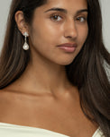 Model wearing the Perlina pearl dangle earrings, front view against a grey backdrop